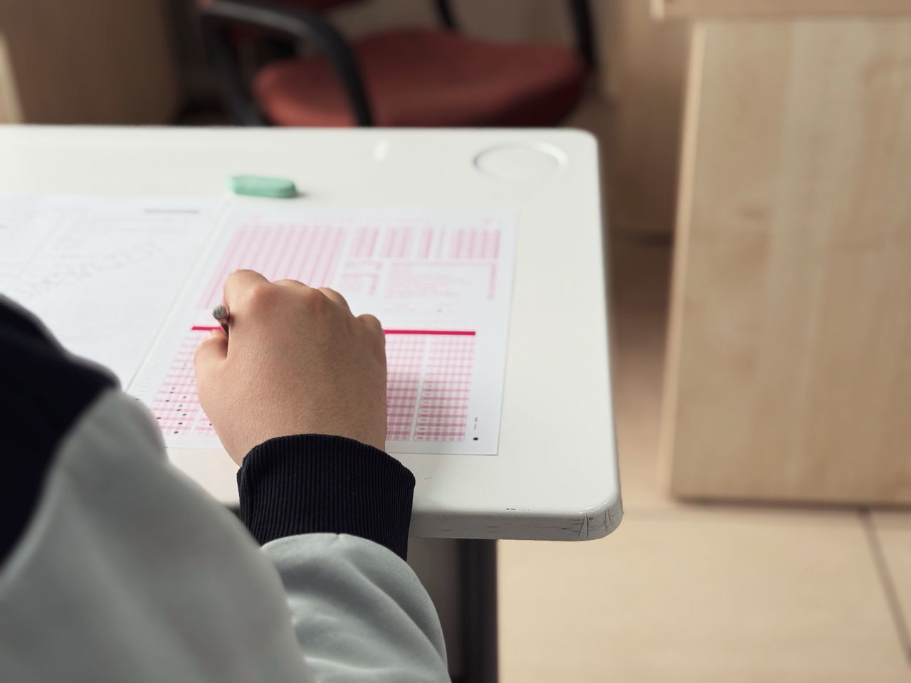 Home Close-up of student answering a test in a classroom environment.